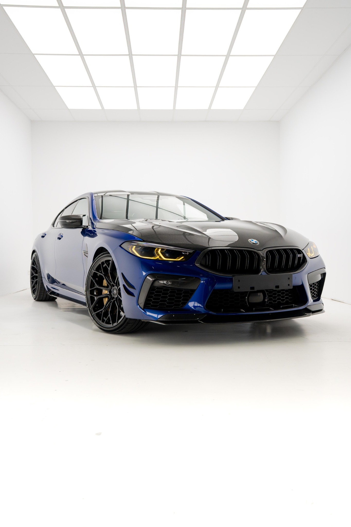 Blauwe BMW met carbon motorkap in een witte studio